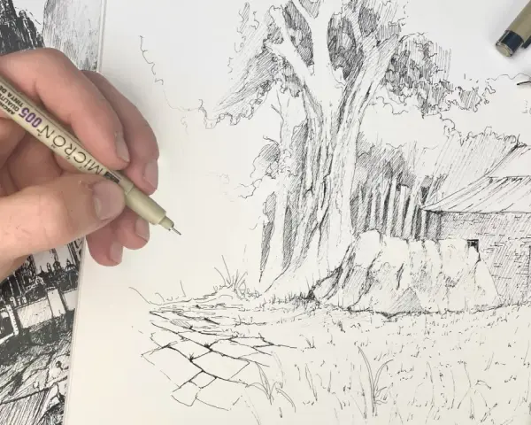 Main d'artiste esquissant une scène rurale avec un gros arbre et une grange. La texture du dessin facile est rendue par des traits fins.