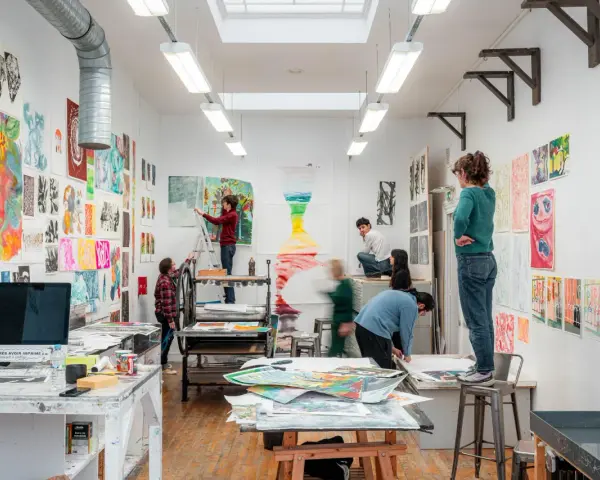 Dans une école d'art animée, des étudiants travaillent sur leurs créations, entourés d'œuvres colorées.