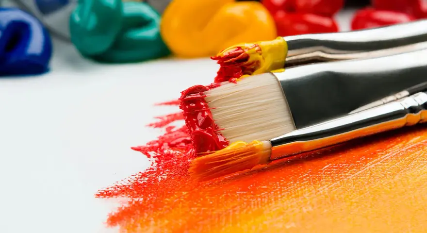 Des pinceaux chargés de peinture rouge et jaune créent une traînée vibrante sur une toile blanche. La question est : peut-on peindre directement sur une toile ? Oui !